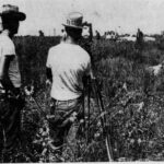 Three men in hats and white t-shirts with a survey transit.