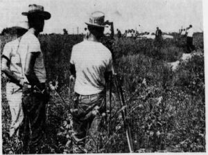 Three men in hats and white t-shirts with a survey transit.