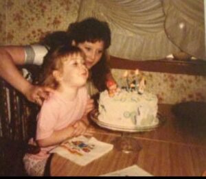 Two females in front of a birthday cake