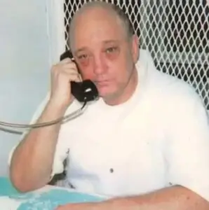 man on death row in white clothing talking on phone