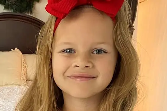 little girl about 6 years old with red bow and honey blond hair
